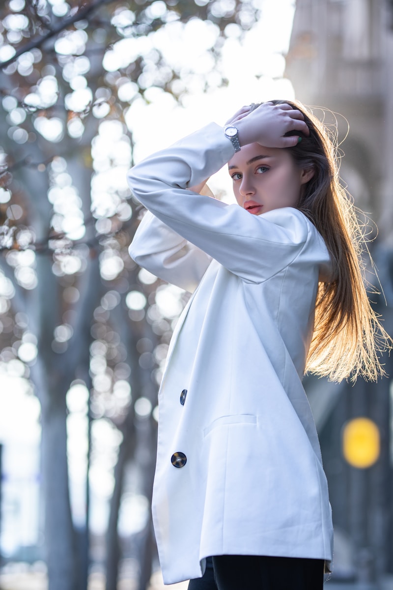 A young woman poses outdoors in a white blazer.