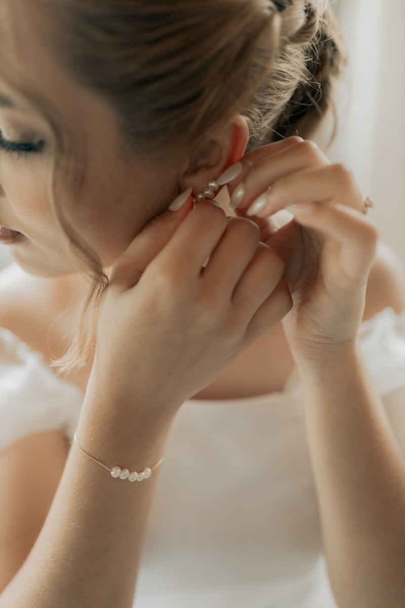 Bride is putting on her elegant earrings.