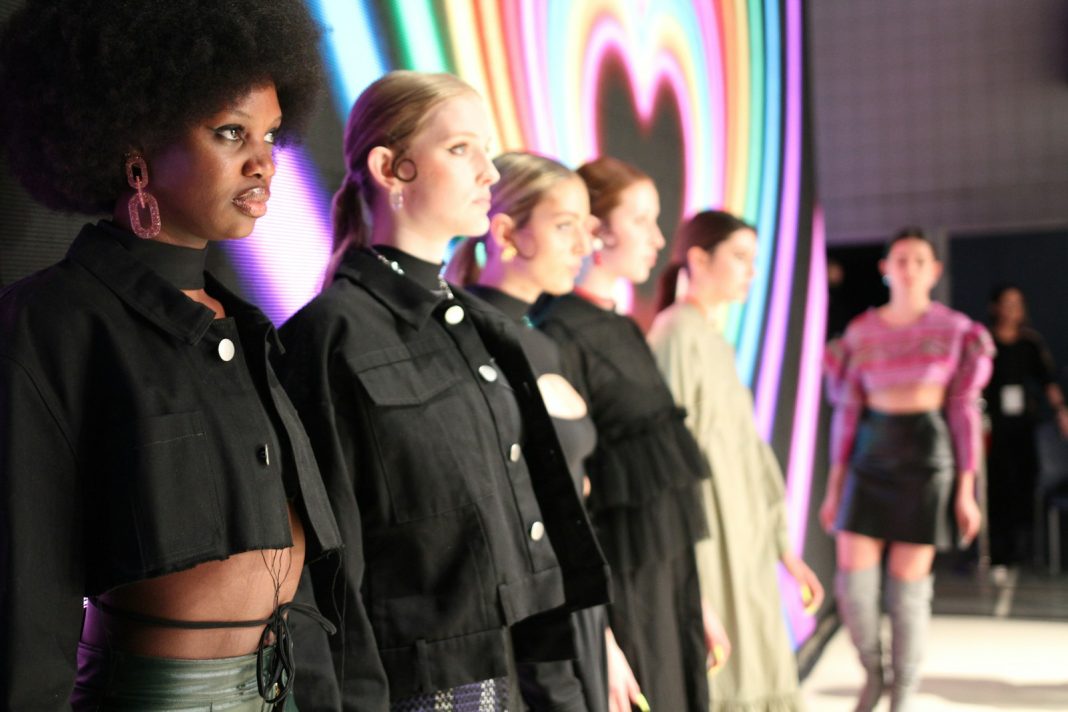a group of women standing next to each other on a runway