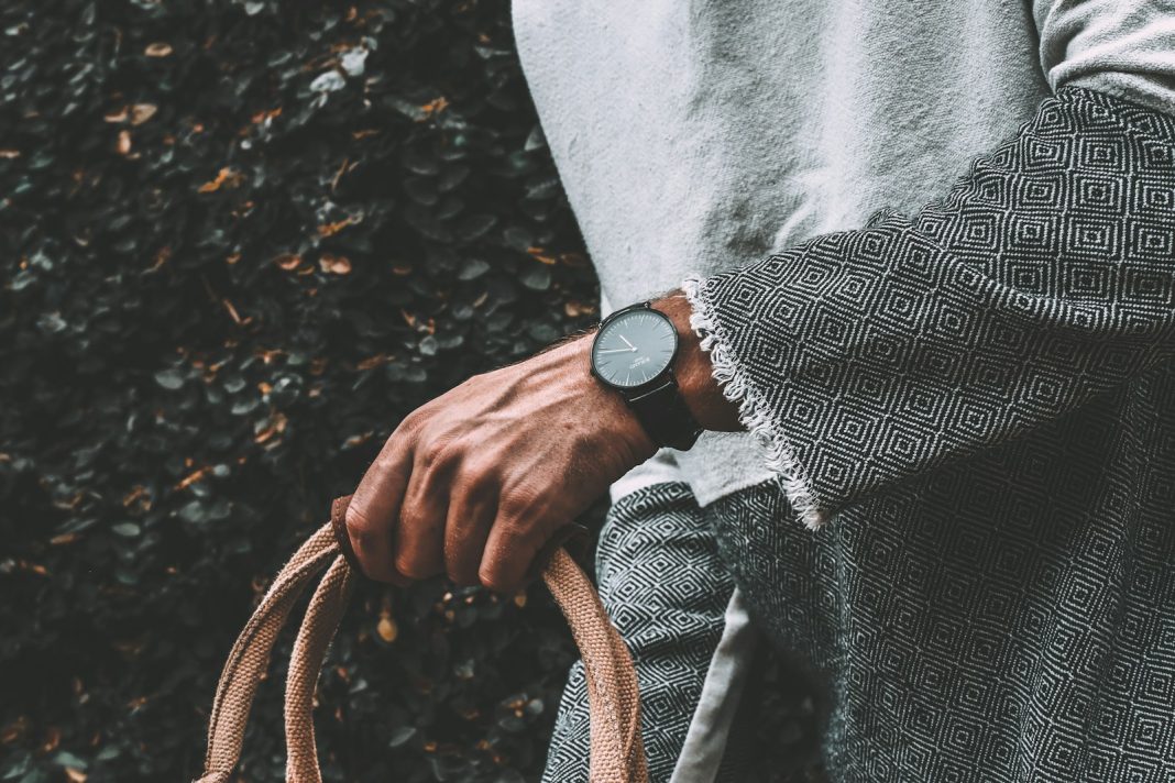 person wearing gray cardigan holding handbag