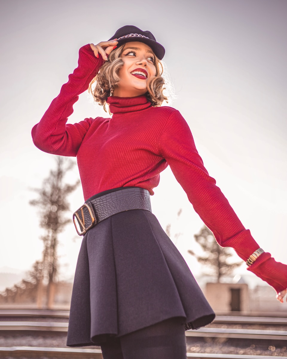 a woman in a red sweater and black skirt