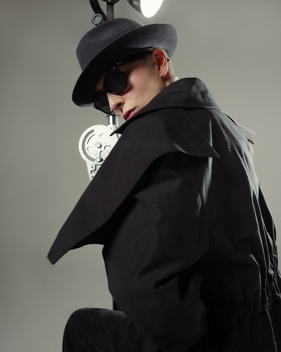 A man in a black coat and hat with a pipe