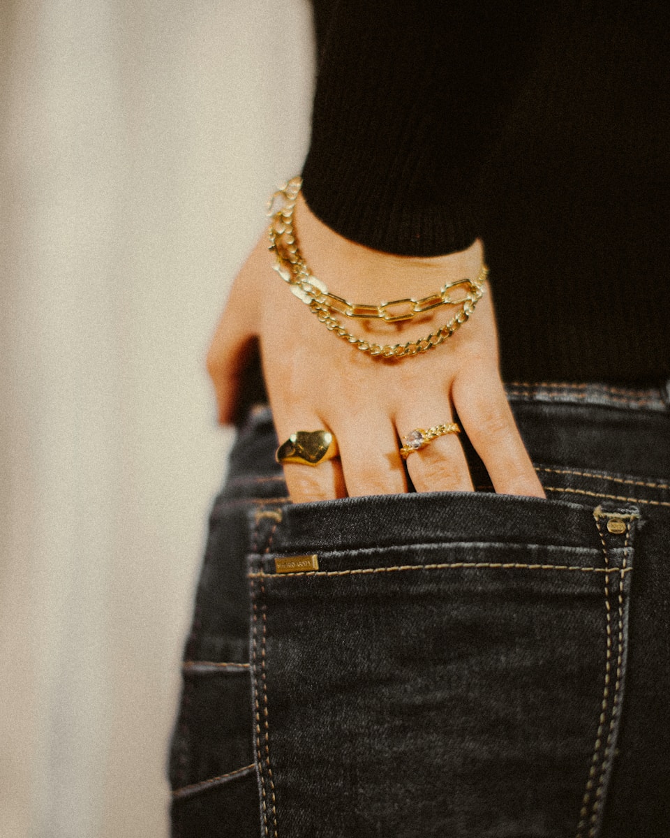 a person wearing a gold chain bracelet and a black shirt