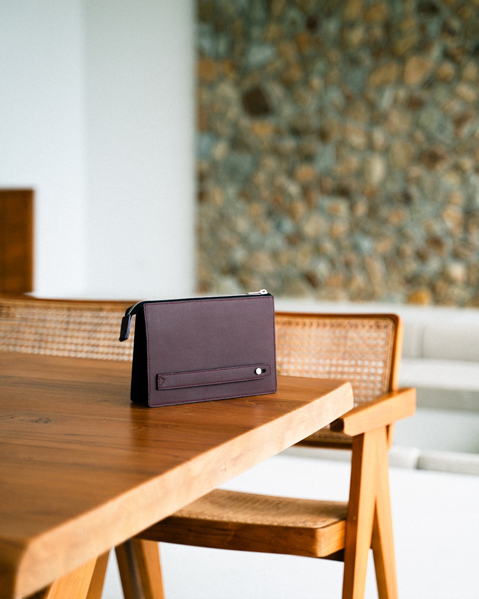 A brown clutch sits on a wooden table.