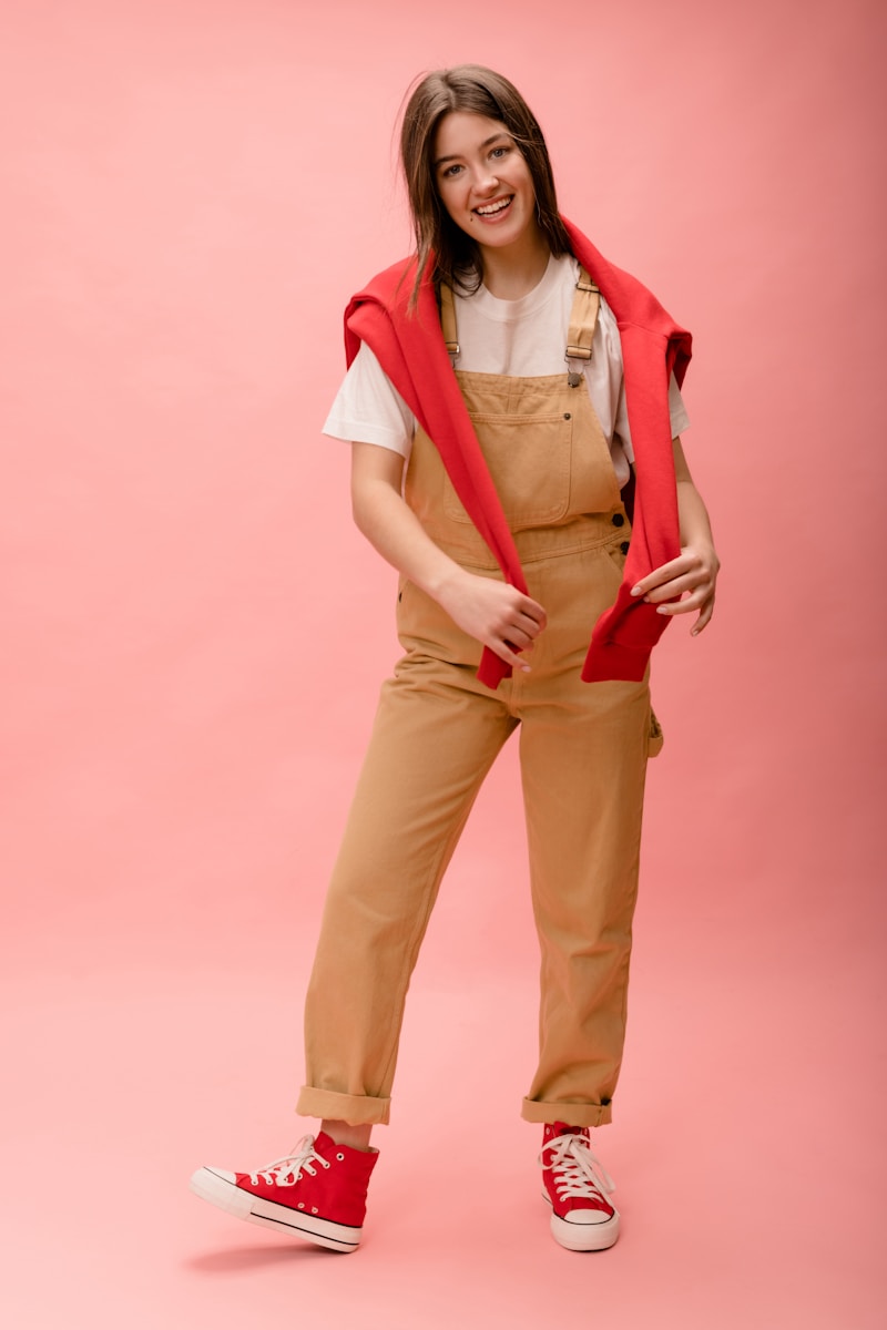 a woman wearing overalls and a red vest